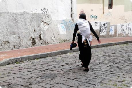 femmes équatorienne traversant une route de Quito portant un bébé dans le dos