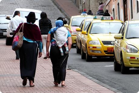 femmes équatoriennes sur un trottoir de Quito dont l'une portant un bébé dans le dos
