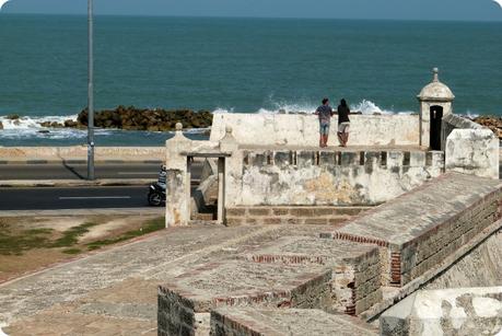 2 hommes de dos accoudés sur les murailles de Carthagène discutant et regardant la mer des Caraïbes en arrière plan