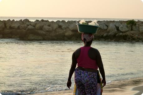 une femme transporte sur sa tête la nourriture qu'elle vend aux vacanciers sur une plage de Carthagène